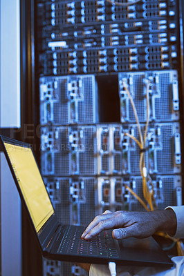 Buy stock photo Closeup shot of an unrecognisable man using a laptop while working in a server room