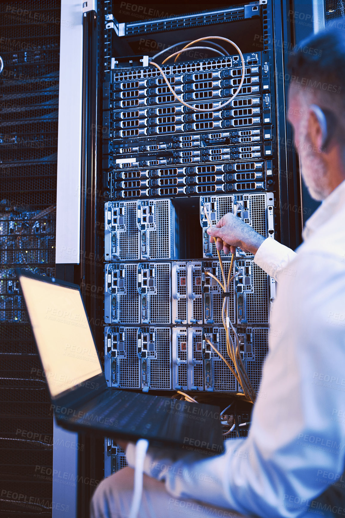 Buy stock photo Rearview shot of a mature man using a laptop while working in a server room