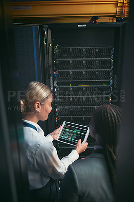 Buy stock photo Shot of two young IT specialists standing in the server room and having a discussion while using a digital tablet