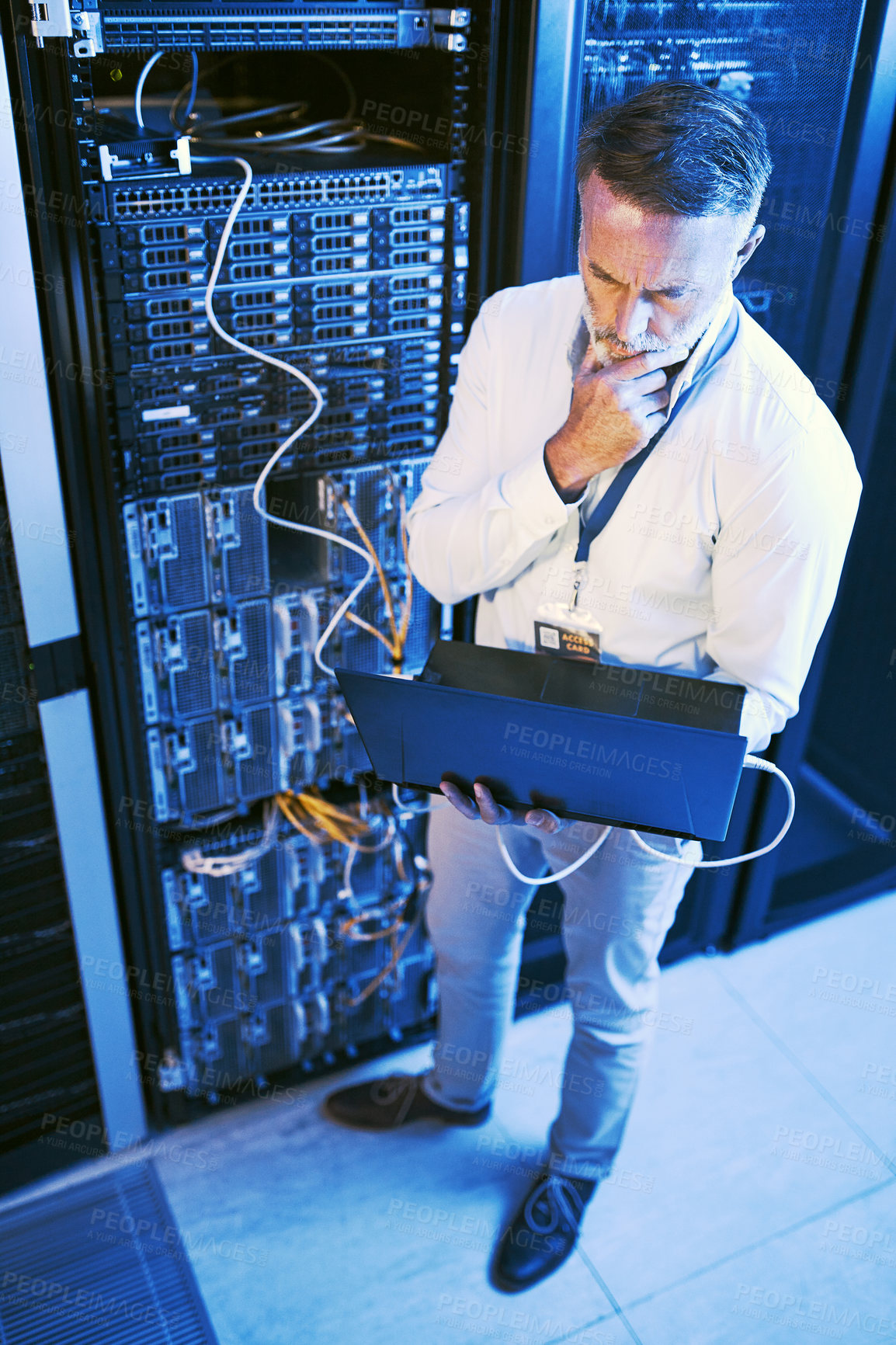 Buy stock photo High angle shot  of a mature man using a laptop while working in a server room