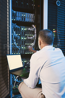 Buy stock photo Rearview shot of a mature man using a laptop while working in a server room