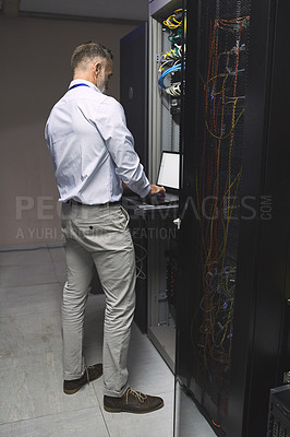 Buy stock photo Rearview shot of a mature man using a laptop while working in a server room