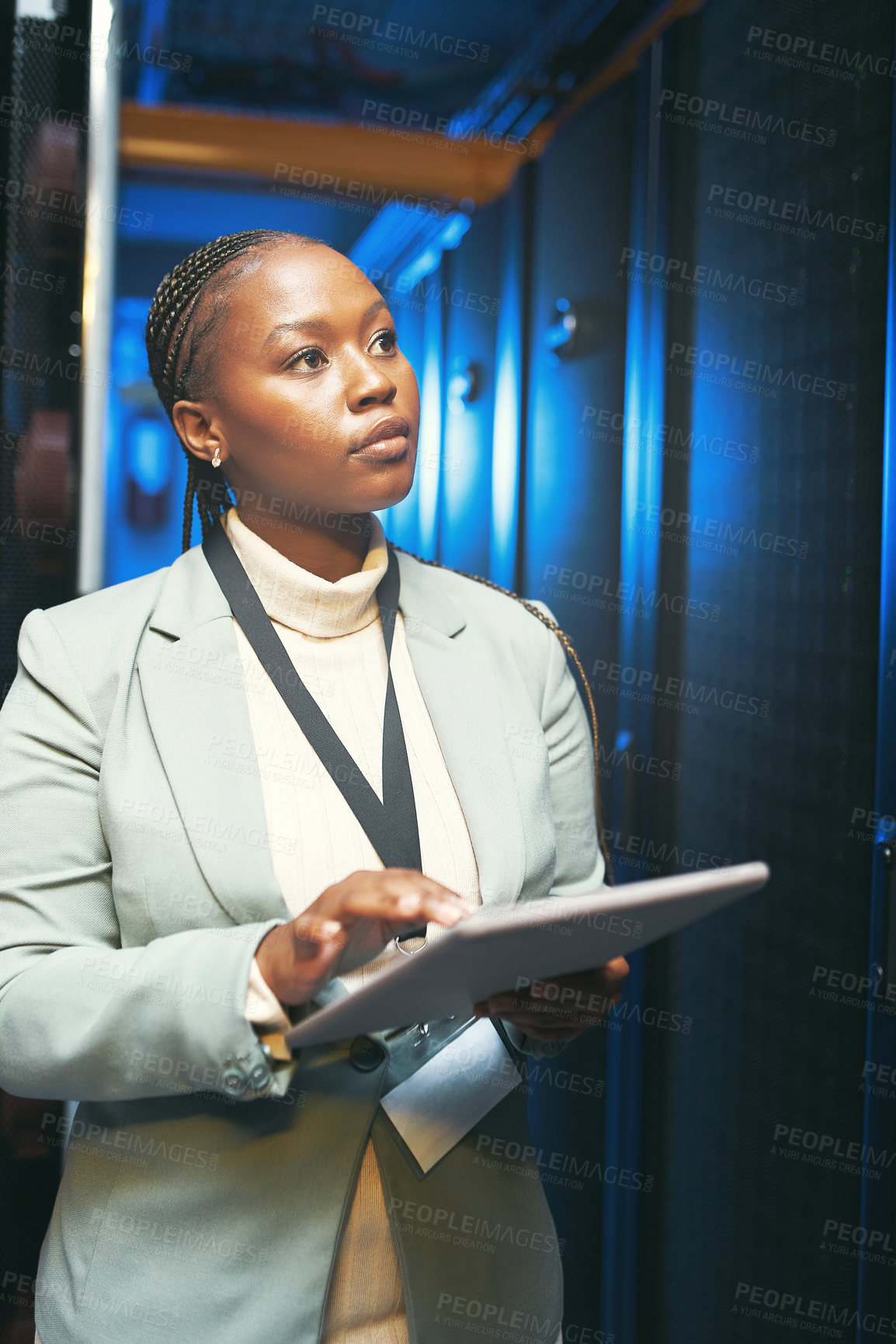 Buy stock photo Shot of a young IT specialist standing alone in the server room and using a digital tablet