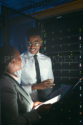 Buy stock photo Shot of two young IT specialists standing in the server room and having a discussion while using a technology