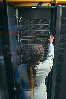 Buy stock photo Shot of an unrecognizable IT specialist standing and working alone in the server room