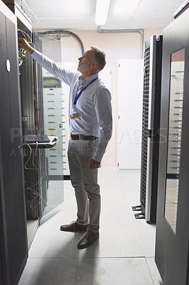 Buy stock photo Shot of a mature man working in a server room