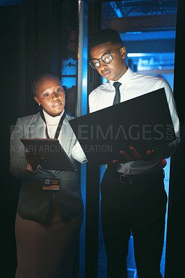 Buy stock photo Shot of two young IT specialists standing in the server room and having a discussion while using a technology