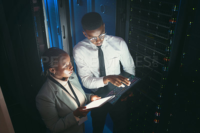 Buy stock photo Shot of two young IT specialists standing in the server room and having a discussion while using a technology
