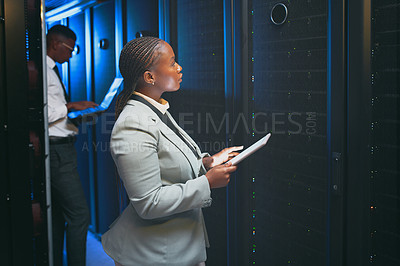 Buy stock photo Shot of two young IT specialists standing together in the server room and using technology