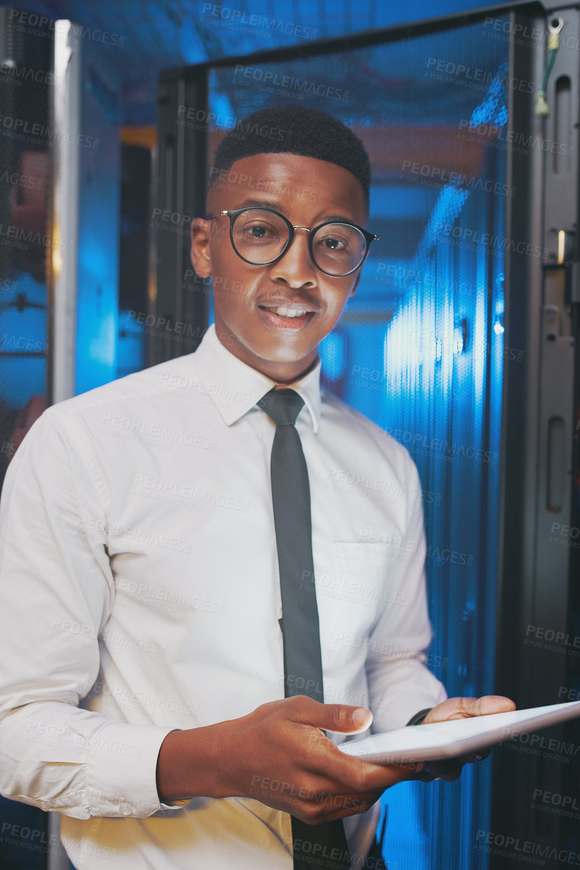 Buy stock photo Shot of a young IT specialist standing alone in the server room and using a digital tablet