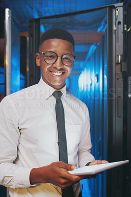 Buy stock photo Shot of a young IT specialist standing alone in the server room and using a digital tablet