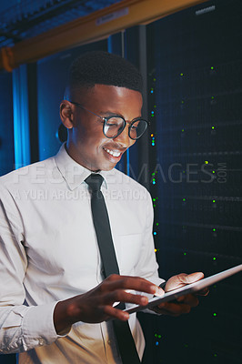 Buy stock photo Shot of a young IT specialist standing alone in the server room and using a digital tablet