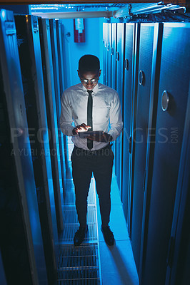 Buy stock photo Full length shot of a young IT specialist standing alone in the server room and using a digital tablet