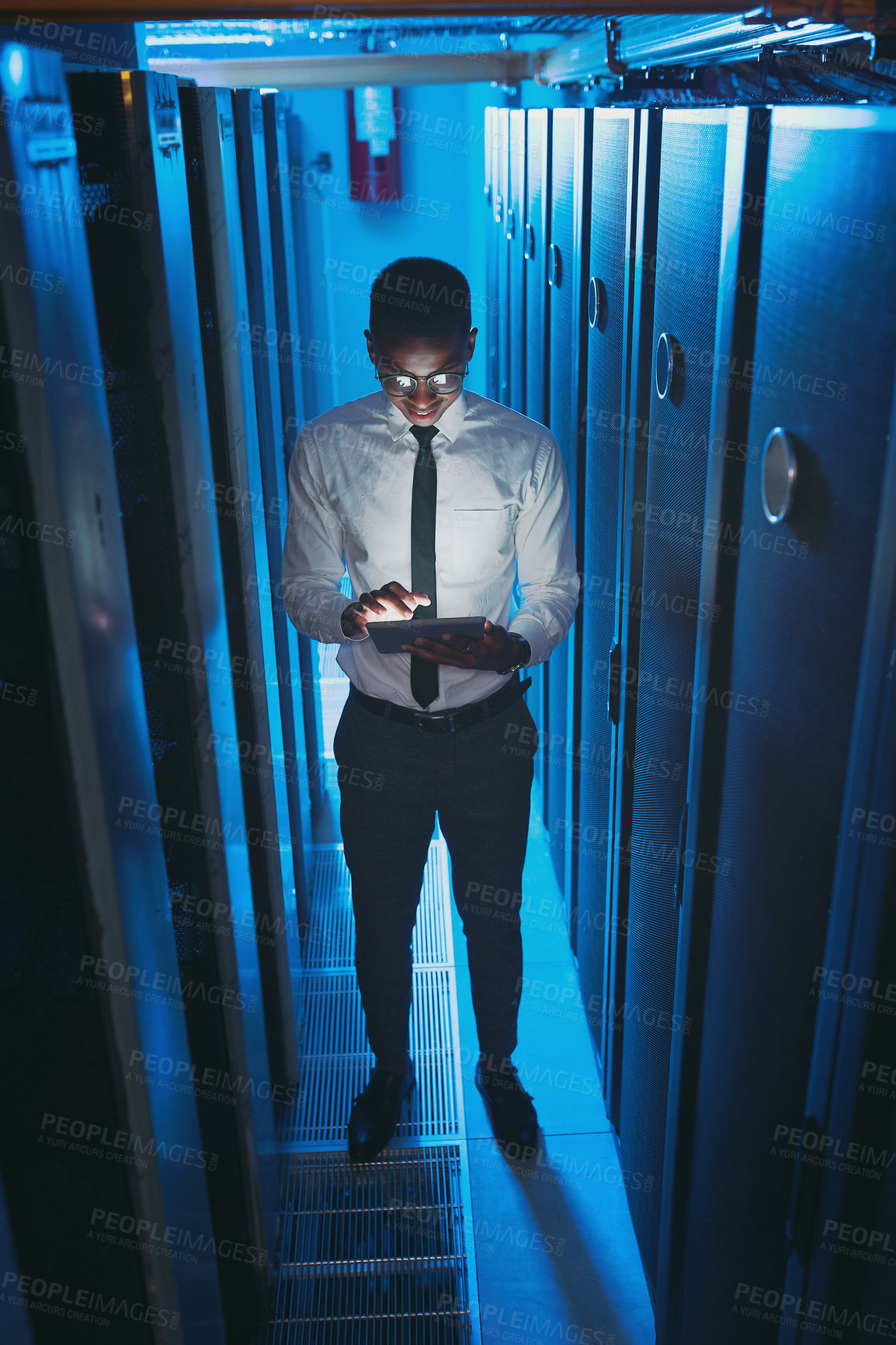 Buy stock photo Full length shot of a young IT specialist standing alone in the server room and using a digital tablet