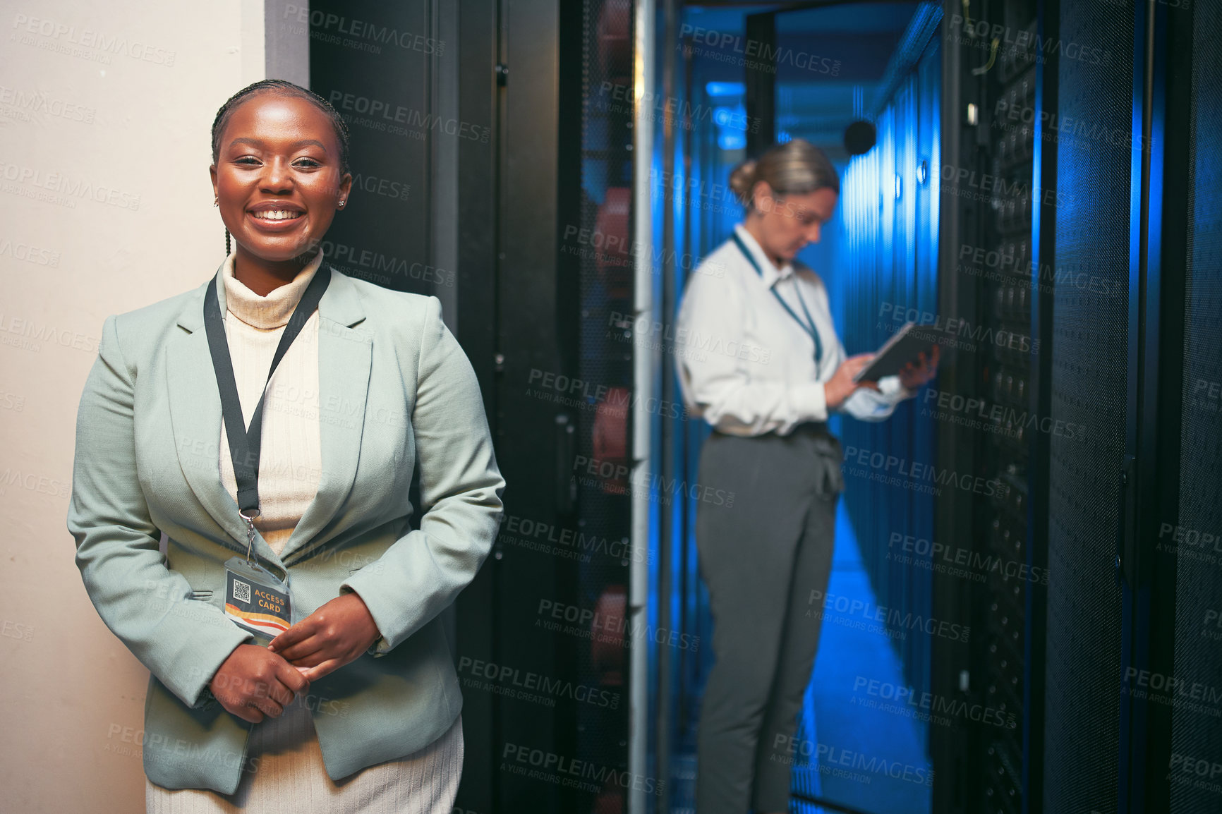 Buy stock photo Shot of two young IT specialists standing together in the server room