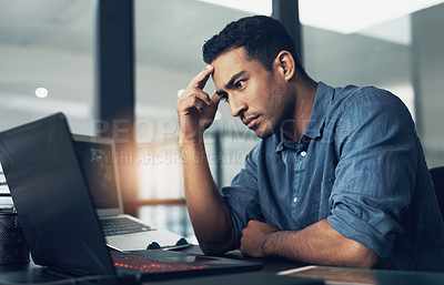 Buy stock photo Shot of a stressed young man using a laptop in a modern office