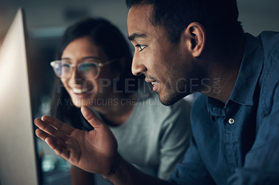 Buy stock photo Shot of two young workers using a laptop in a modern office