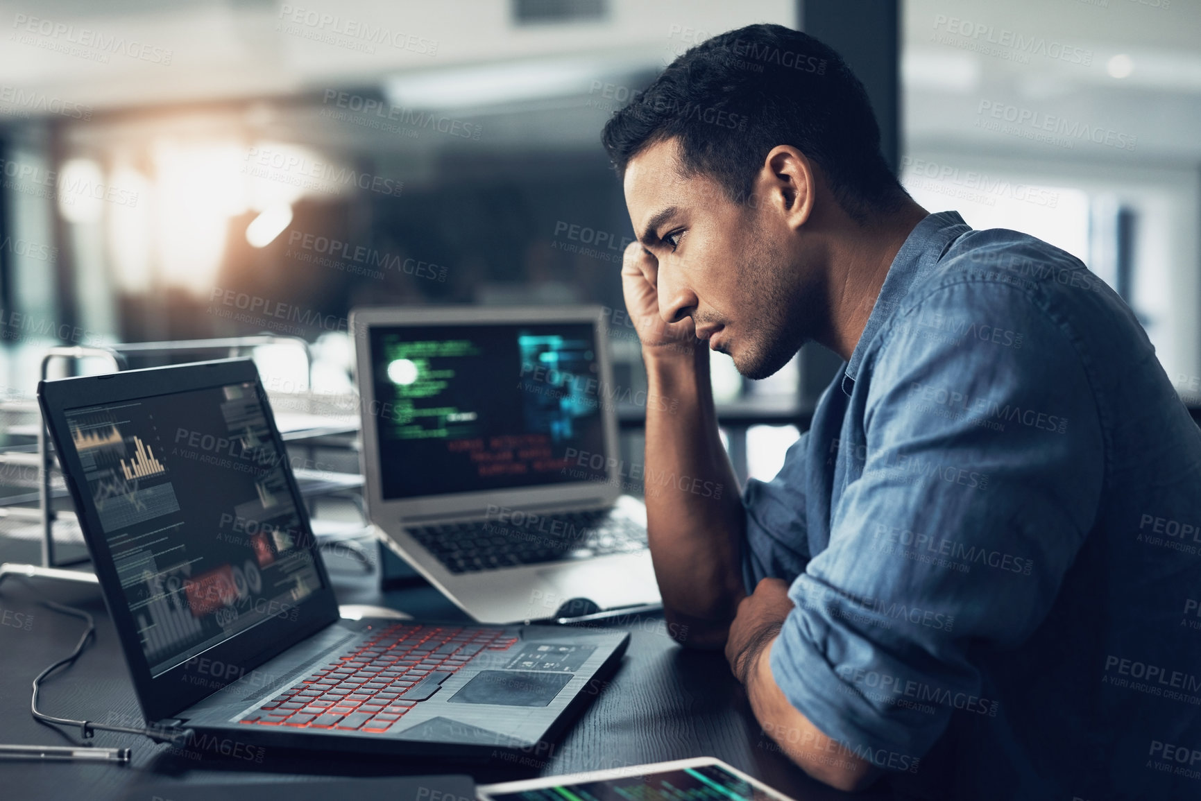 Buy stock photo Shot of a young man suffering from a headache while using a laptop in a modern office