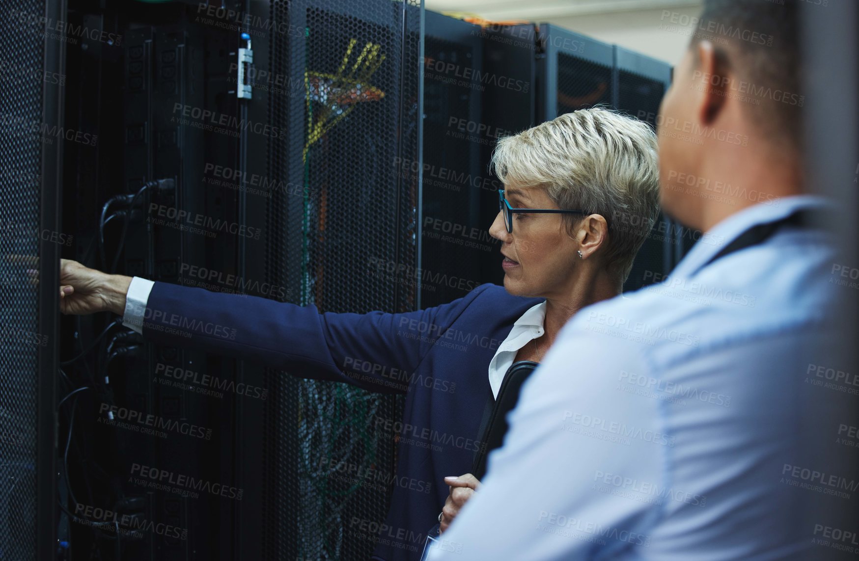 Buy stock photo Shot of two workers inspecting the electronic equipment in a server room together at work