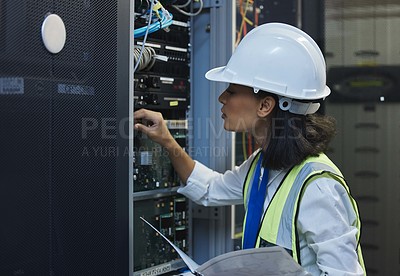 Buy stock photo Shot of a young woman working on cables in a server room