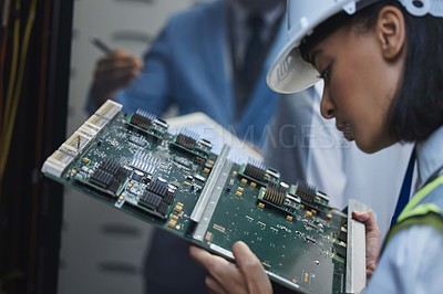 Buy stock photo Shot of a young woman closely inspecting a motherboard in a server room