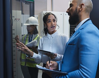 Buy stock photo Shot of two workers inspecting the electronic equipment in a server room together at work