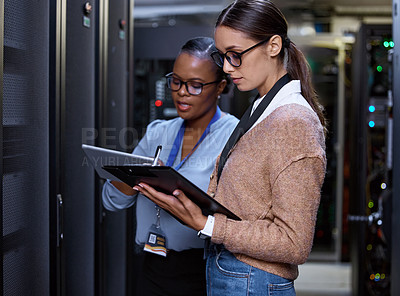 Buy stock photo Cropped shot of two attractive young female computer programmers working together in a server room