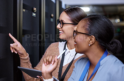 Buy stock photo Cropped shot of two attractive young female computer programmers working together in a server room