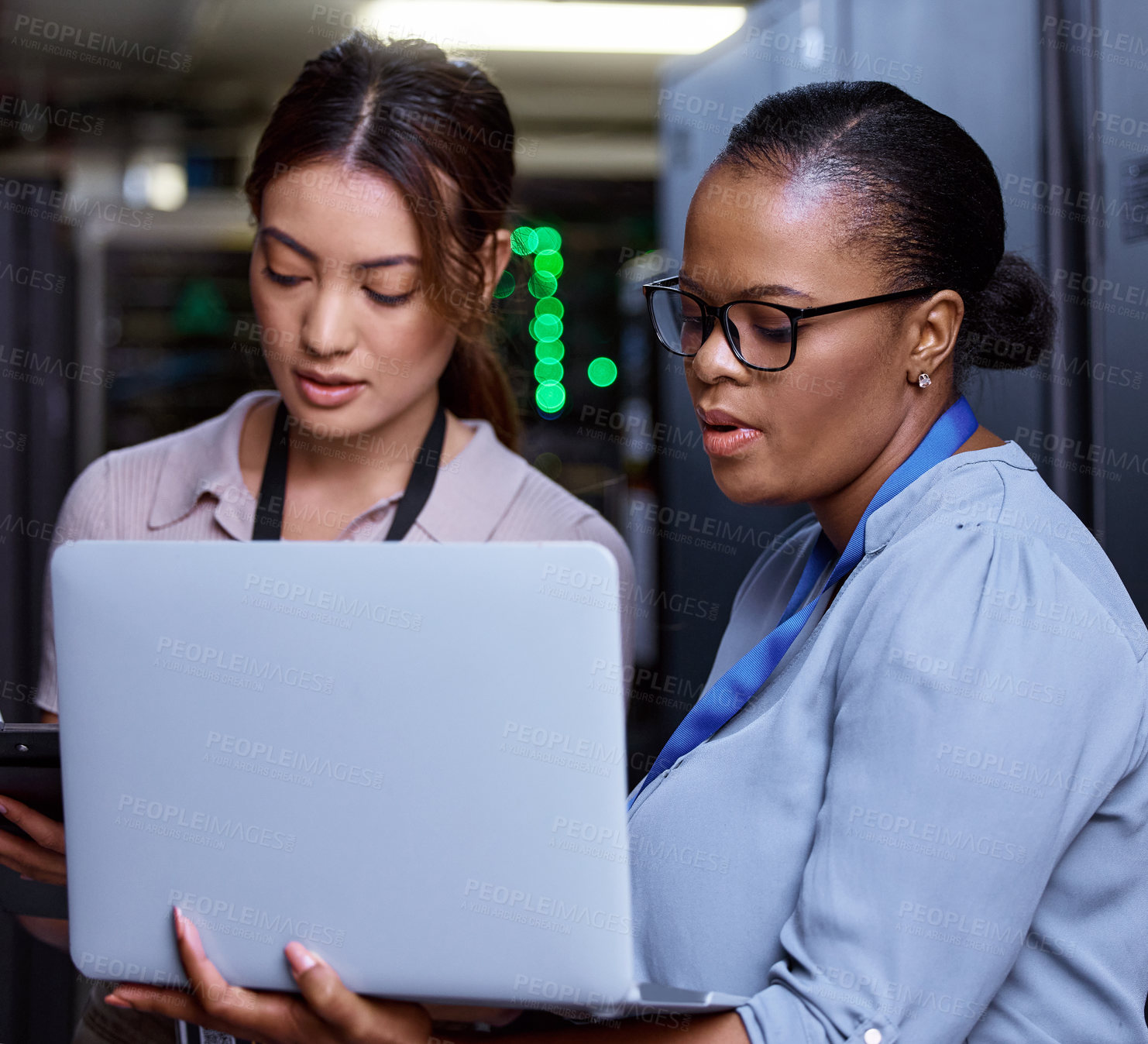 Buy stock photo Cropped shot of two attractive young female computer programmers working together in a server room