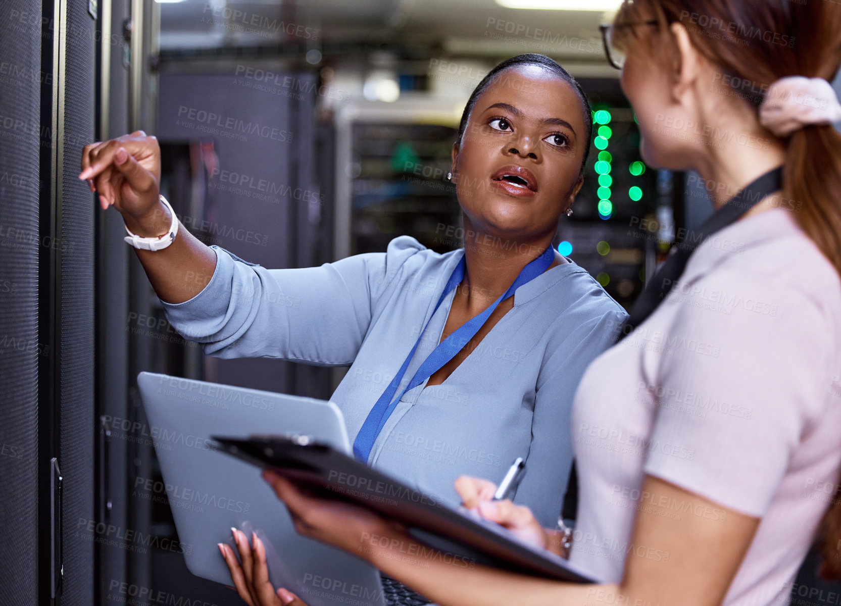 Buy stock photo Cropped shot of two attractive young female computer programmers working together in a server room