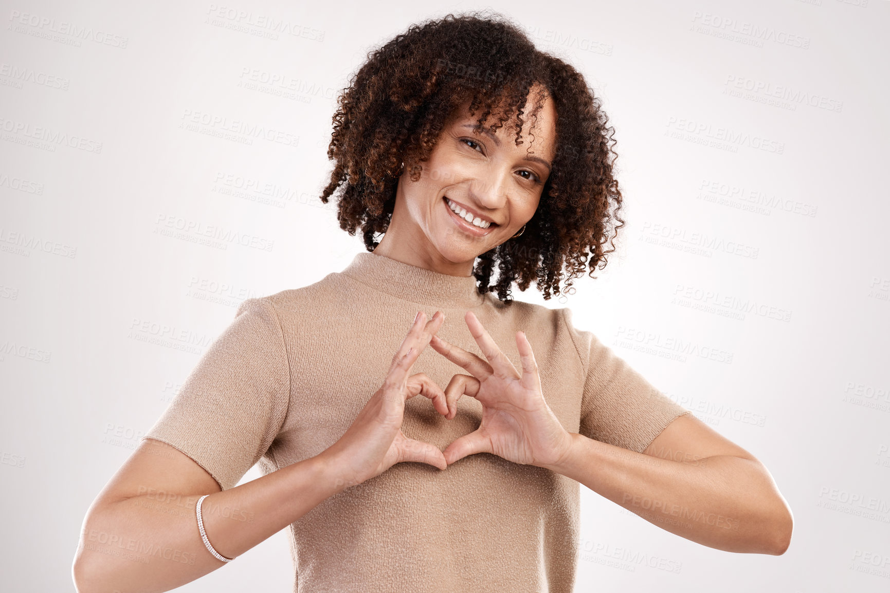 Buy stock photo Cropped portrait of an attractive young woman making a heart shape with her hands in studio against a grey background