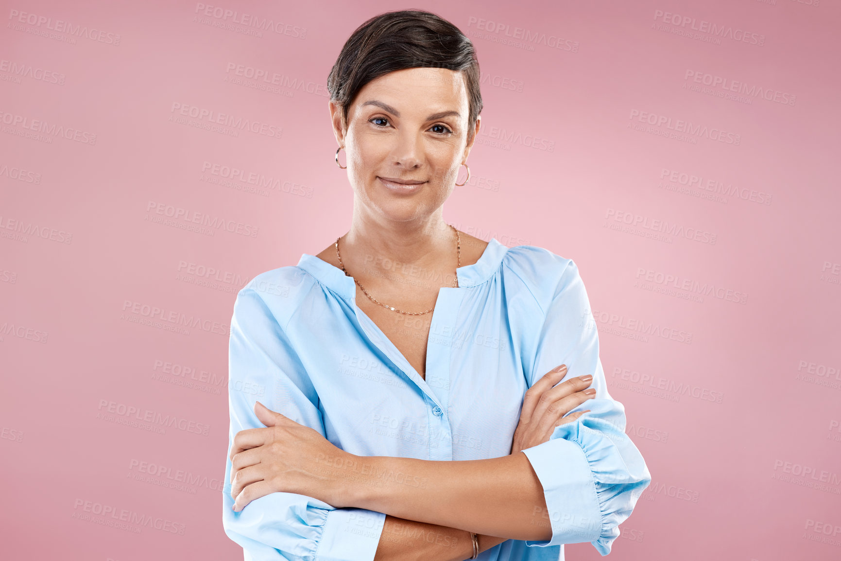 Buy stock photo Cropped portrait of an attractive young woman standing with her arms folded in studio against a pink background