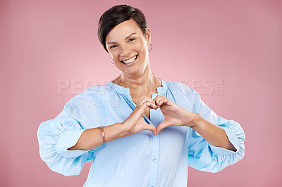 Buy stock photo Cropped portrait of an attractive young woman making a heart shape with her hands in studio against a pink background
