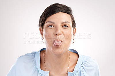 Buy stock photo Cropped portrait of an attractive young woman pulling tongue in studio against a grey background
