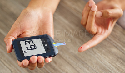 Buy stock photo High angle shot of an unrecognizable woman testing her blood sugar level at home