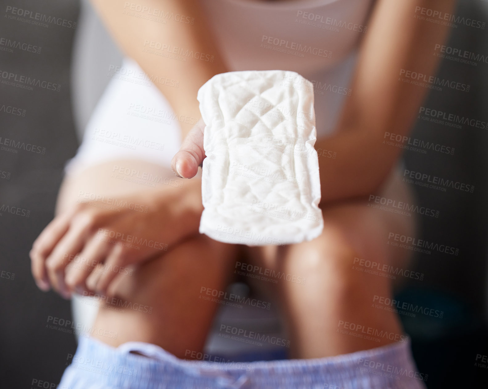 Buy stock photo Shot of an unrecognizable woman holding a sanitary towel in a bathroom at home