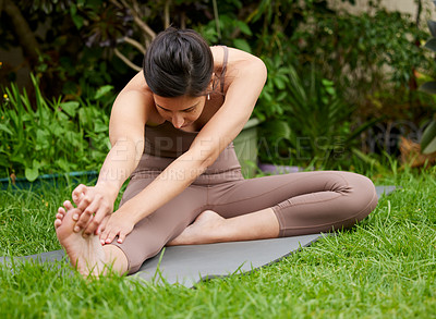 Buy stock photo Shot of a young woman stretching her legs while exercising outdoors