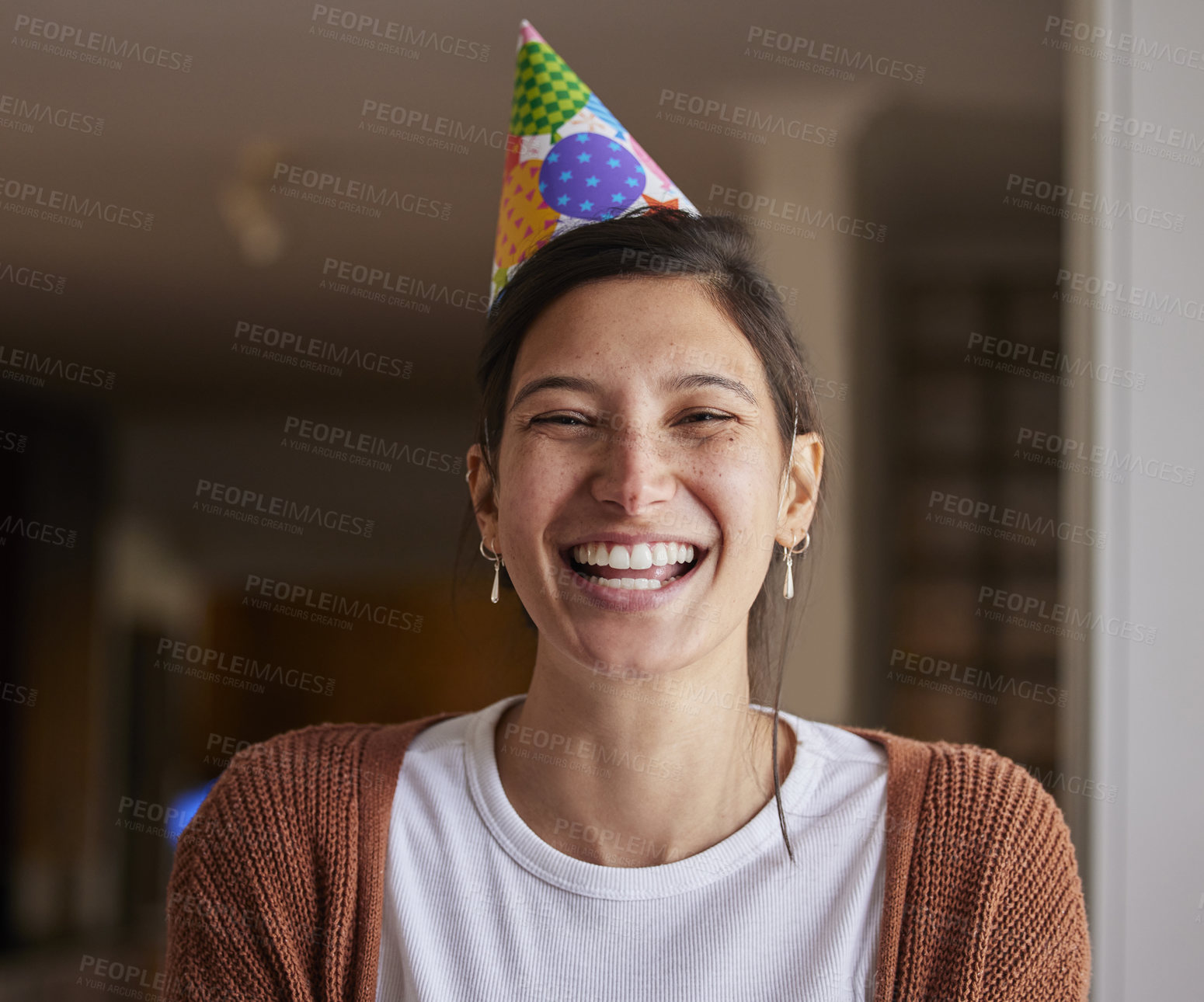 Buy stock photo Portrait of a cheerful young woman wearing a party hat at home