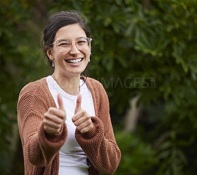 Buy stock photo Portrait of a cheerful young woman showing thumbs up outdoors