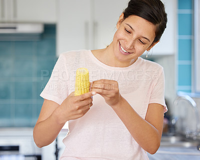 Buy stock photo Shot of a young woman preparing corn to be cooked