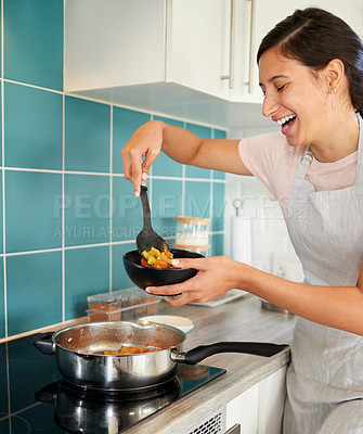 Buy stock photo Shot of a young woman dishing up some of the food she just prepared