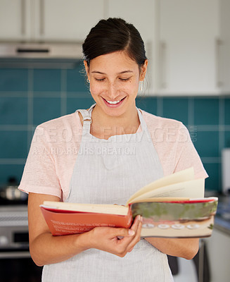Buy stock photo Shot of a young woman reading a cook book