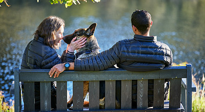 Buy stock photo Couple, dog and back on park bench, outdoor and relax by lake for connection, care or touch on holiday. Man, woman and pet animal by water with German shepherd for trust, vacation or nature in winter