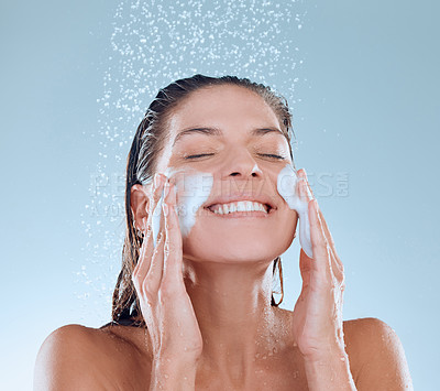 Buy stock photo Woman, facial and soap in shower for skincare hygiene, wash or clean against a blue studio background. Happy, splash and model person for wellness of face, cosmetics or healthy treatment by water