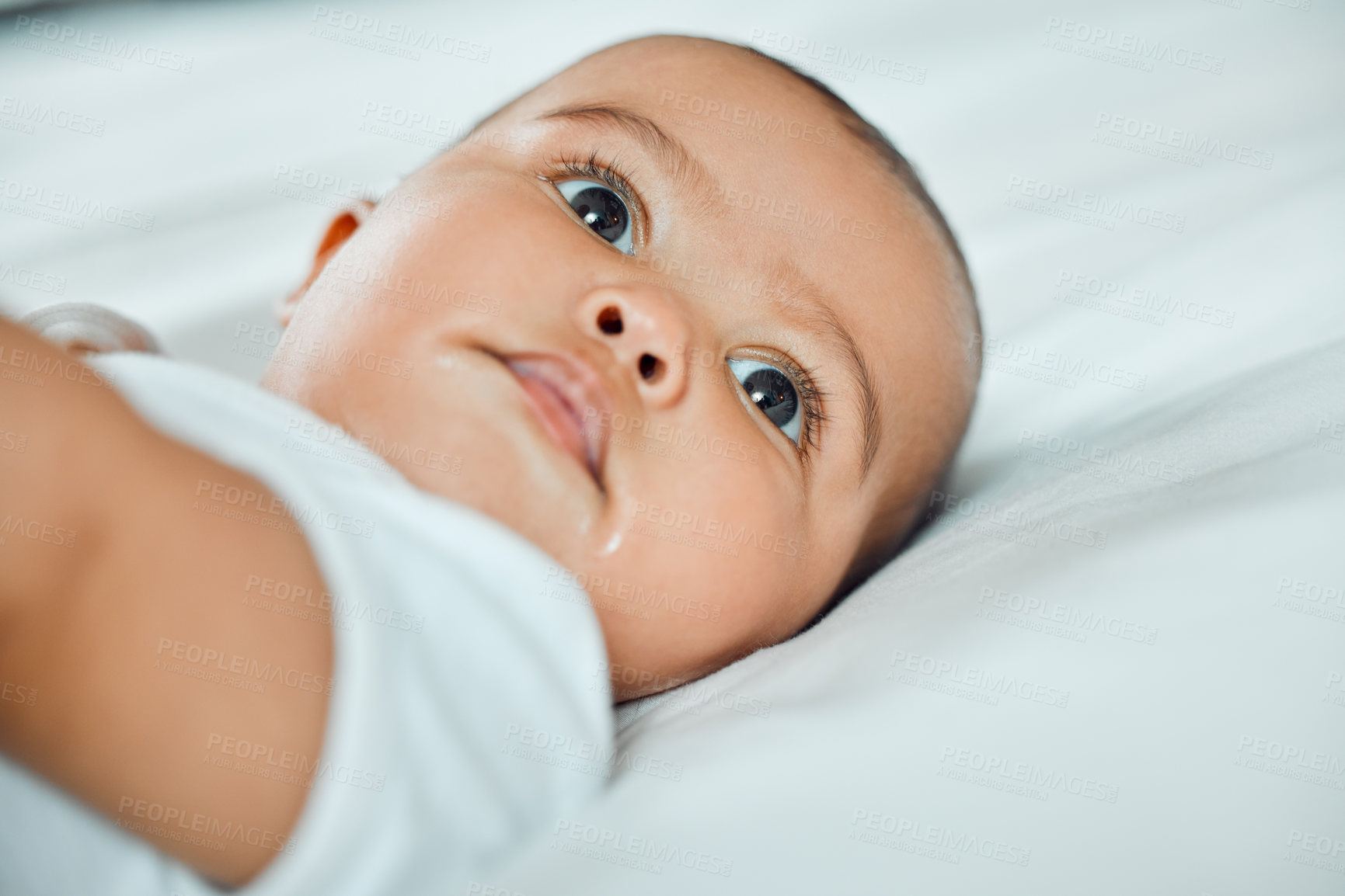 Buy stock photo Shot of an adorable baby boy lying on a bed