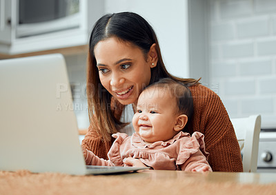 Buy stock photo Cropped shot of an attractive young woman working at home with her newborn baby sitting on her laptop