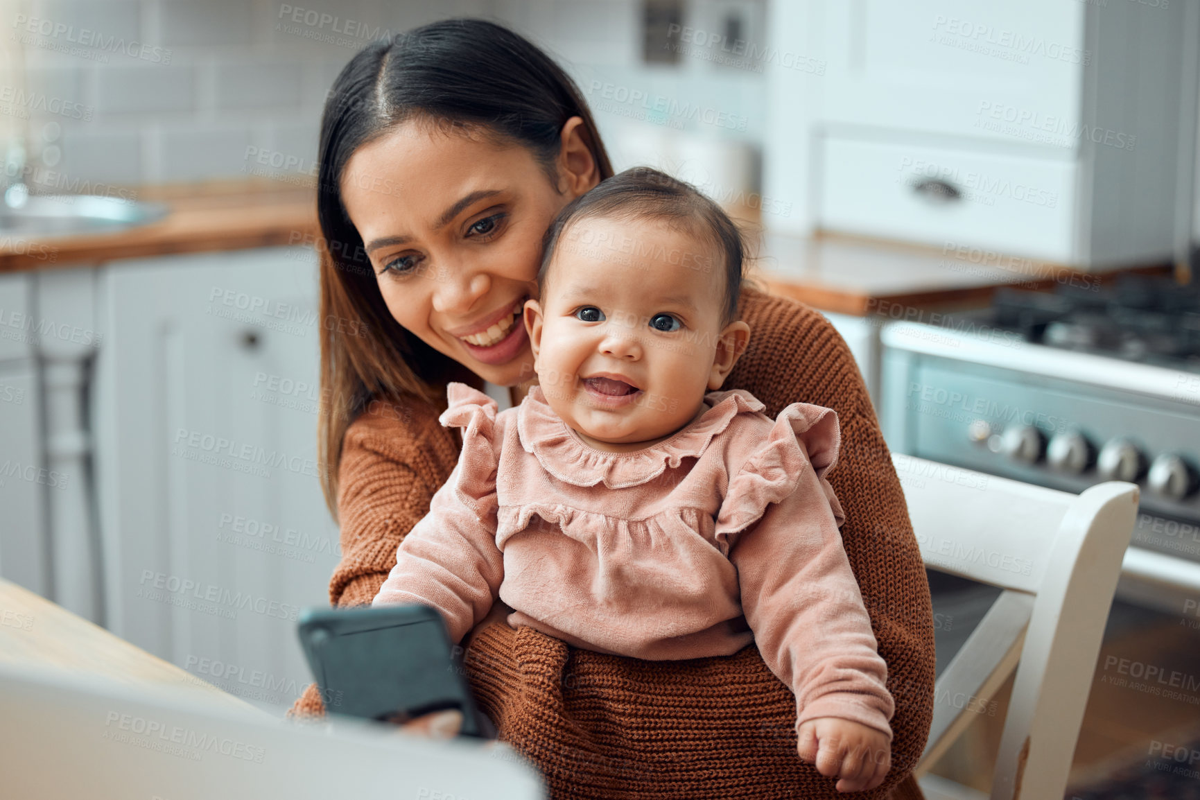 Buy stock photo Cropped shot of an attractive young woman working at home with her newborn baby sitting on her laptop