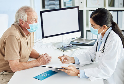 Buy stock photo Shot of a doctor wearing a face mask and sitting with her senior patient during a consult in her clinic