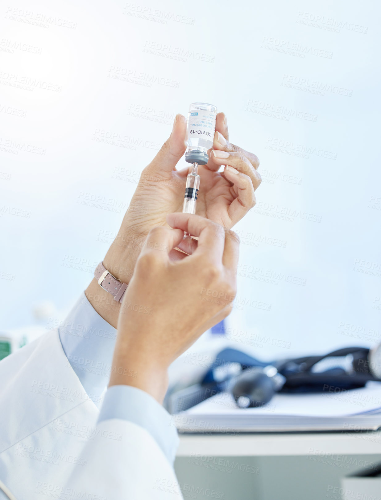 Buy stock photo Cropped shot of an unrecognizable doctor using a syringe to draw out the Covid vaccine in her clinic