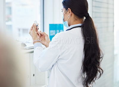 Buy stock photo Shot of an unrecognizable doctor standing and using a syringe to draw out the Covid vaccine in her clinic